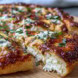 Sliced Hot Honey Ricotta Pizza on a wooden board, drizzled with spicy honey.