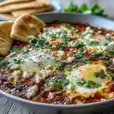 Steaming Shakshuka Bowl featuring runny egg yolks in a rich pepper and tomato stew, garnished with fresh cilantro.