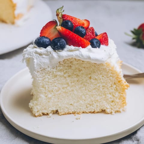 A light and airy slice of Angel Food Cake, showcasing its delicate, sponge-like crumb inside.