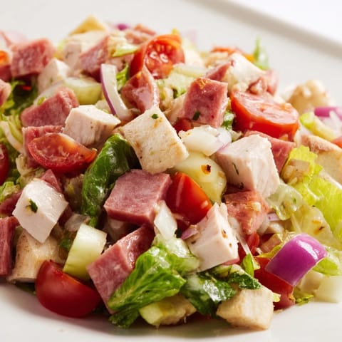 Freshly tossed Italian Deli Chopped Chicken Salad glistens with a tangy herb dressing, red onion, cucumber, and melted provolone cheese in a rustic setting.  