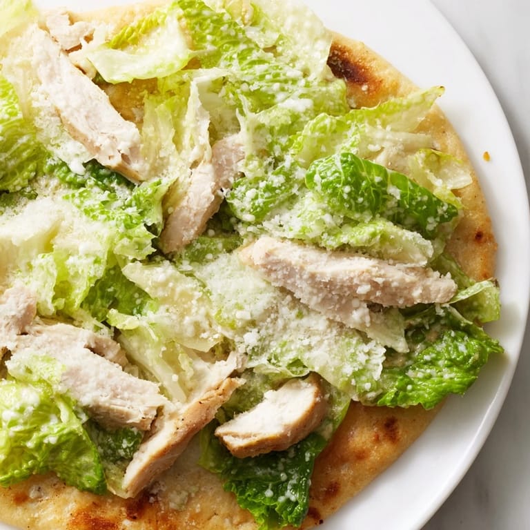 Sliced Chicken Caesar Flatbread served hot on a wooden board, perfect for a light lunch or appetizer.