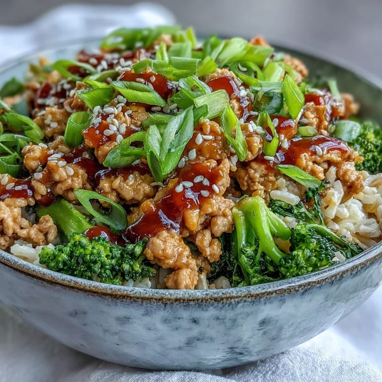 Overhead shot of Sweet and Spicy Turkey Broccoli Bowls showing glazed turkey and bright green broccoli florets on brown rice, with a drizzle of sriracha-honey sauce.