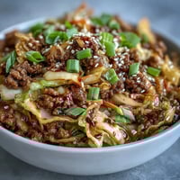 Sizzling ground pork sautéed with garlic, ginger, and onions, creating a savory base for this quick Egg Roll in a Bowl.